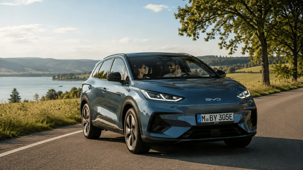 Paar fährt mit BYD SUV im Auto Abo entlang eines Sees durch die Landschaft