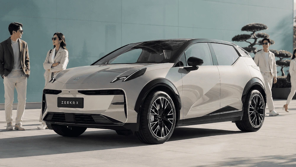 Zeekr X Elektro-SUV in Silber mit schwarzem Kontrastdach, Passanten stehen davor auf einem Platz vor einer Glasfassade (Symbolbild)