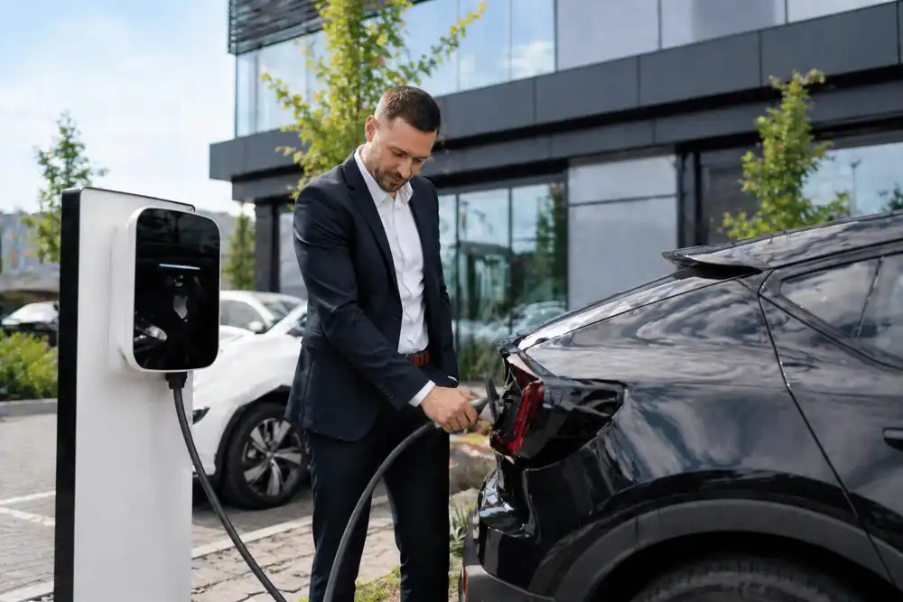 Laden im Alltag: Elektromobilität für Berufspendler Geschäftsmann lädt sein Elektroauto an einer öffentlichen Ladesäule vor einem Bürogebäude