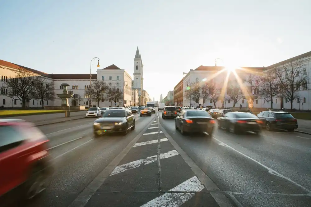 Dichter Stadtverkehr auf einer mehrspurigen Straße in einer deutschen Innenstadt bei Sonnenuntergang